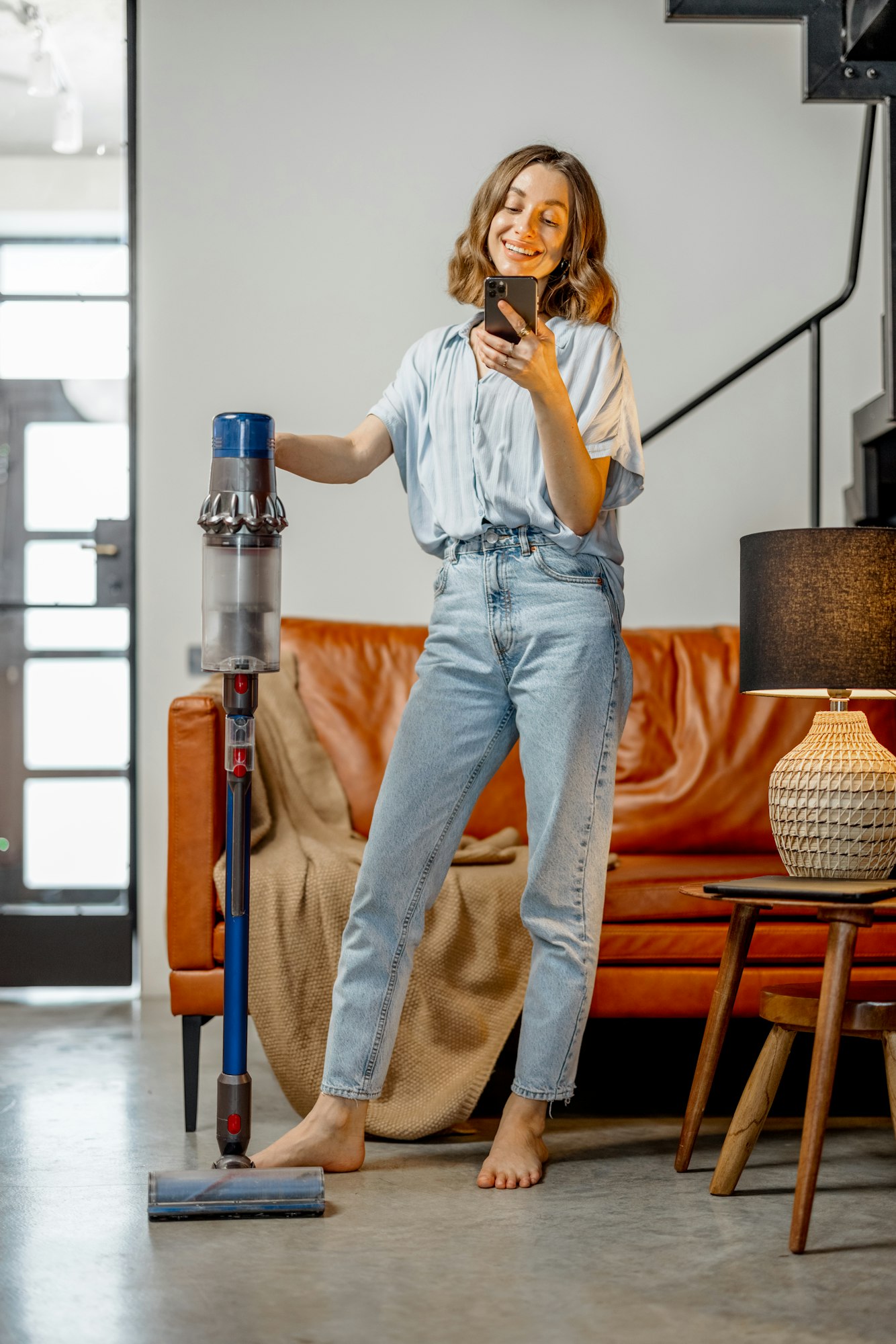 Woman with cordless vacuum cleaning floor at home